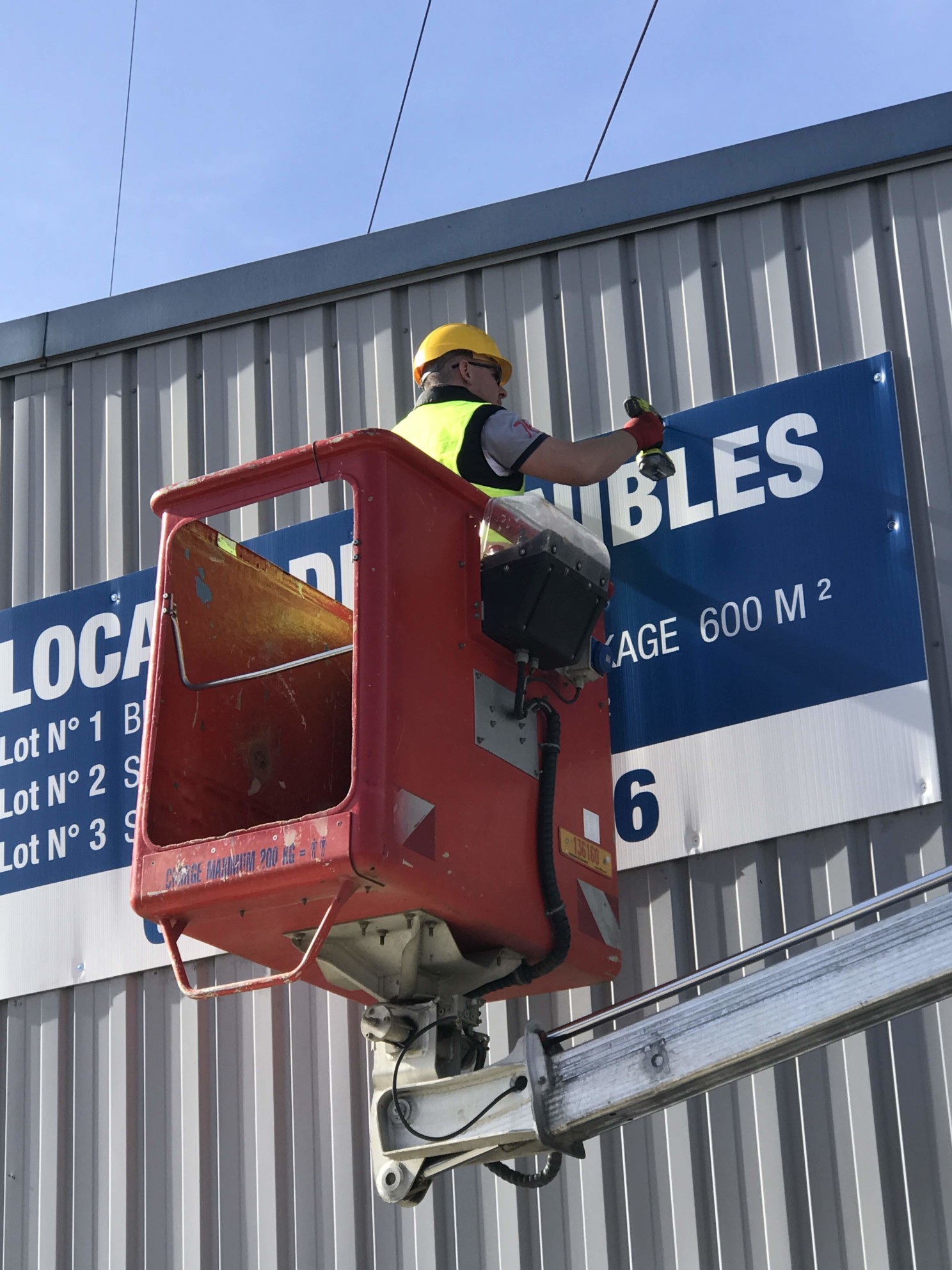 Poseur installant une signalétique en hauteur